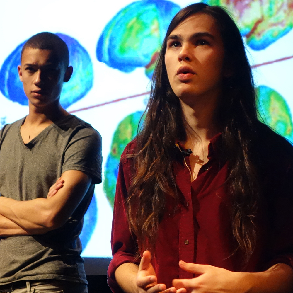 Male and female participants stood in front of brain scans